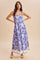 woman wearing a purple floral maxi dress with a fitted bodice and flowing skirt, posing confidently