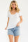 woman wearing a white short sleeve top with blue floral print and light denim cut-off shorts