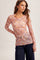 woman wearing a pink floral long sleeve top with a fitted silhouette and scalloped hem, styled with denim jeans