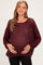 woman wearing a burgundy open knit maternity sweater and holding her baby bump