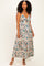 woman wearing a floral print maternity maxi dress with a tied front and tiered skirt, standing and smiling