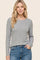 woman wearing a gray long sleeve ribbed top with a round neckline and smiling in a casual pose