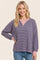 woman wearing a striped oversized pullover sweatshirt in purple and pink with a relaxed fit and long sleeves