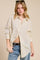 woman wearing a cream button-up shirt with black polka dots and distressed jeans, styled with sunglasses in her hair