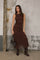 woman wearing a brown lace midi dress with a fitted silhouette and long dark boots, holding a small handbag