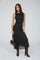 woman wearing a black lace midi dress with a fitted silhouette and knee-high brown boots, holding a small handbag