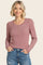 woman wearing a red and white striped long sleeve henley top with button details and smiling at the camera