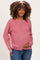 woman wearing a pink maternity sweater with a textured knit and holding her baby bump
