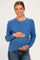 woman wearing a blue textured maternity sweater and holding her baby bump