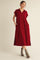 woman wearing a burgundy oversized dress with a collared neck and pockets, paired with gray ankle boots