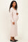 woman wearing a light pink long sleeve maternity dress, gently cradling her baby bump while standing sideways