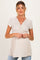 woman wearing a beige short sleeve maternity top with a wrapped front and visible baby bump