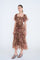 woman wearing a brown floral maxi dress with puff sleeves and tiered ruffles, standing against a white background