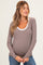 woman wearing a brown and white striped long sleeve maternity top and showing her baby bump