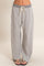 woman wearing gray lounge pants with a drawstring waistband and wide legs, standing against a neutral background