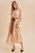 woman wearing a light peach floral maxi dress with long sleeves and a brown belt, paired with matching heels