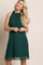 woman wearing a dark green maternity dress with a ruffled neckline and a flowing skirt, showcasing a baby bump