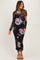 woman wearing a black floral maternity dress with long sleeves and a fitted silhouette