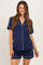 woman wearing a navy blue short sleeve maternity pajama set with white piping and a visible baby bump