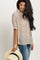 Woman wearing a cream polka dot button-down blouse and distressed jeans holding a straw sun hat