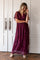 woman wearing a burgundy maxi dress with floral embroidery and short flutter sleeves, standing and smiling