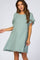 woman wearing a mint green loose-fitting maternity dress with fringe details on the sleeves