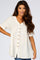 woman wearing a cream short sleeve button down babydoll top with v-neckline