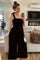 woman wearing a black velvet wide-leg jumpsuit with a square neckline, standing in a bright living room