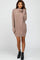 woman wearing a taupe oversized sweater dress with a cowl neck and long sleeves, paired with black ankle boots