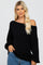 blonde woman wearing a black off-the-shoulder knit sweater and blue jeans