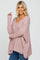 blonde woman wearing a dusty rose oversized v-neck knit sweater and blue jeans