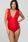 woman wearing a red ruffled maternity swimsuit, posing with a visible baby bump