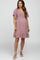 woman wearing a mauve maternity dress with flutter sleeves and a ruffled hem, showing her baby bump