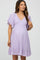 woman wearing a lavender maternity dress with flutter sleeves and a smocked bodice, showing off her baby bump