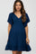 woman wearing a navy blue maternity dress with a smocked bodice and flutter sleeves, showcasing her baby bump