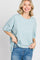 woman wearing a light blue oversized t-shirt and jeans, smiling at the camera