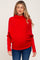 woman wearing a red maternity sweater with a cowl neck and loose fit, highlighting her baby bump