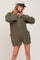 woman wearing olive green knit button-front romper with pockets and a tan baker boy hat