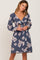 woman wearing a navy blue floral print dress with long sleeves and a tie front detail