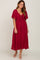 woman wearing a burgundy flutter sleeve midi dress with a front tie detail and white sandals