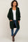 woman wearing a dark green long cardigan with pockets, paired with a white top and blue jeans