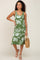 woman wearing a green floral knit midi dress and holding a straw bag