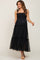 woman wearing a black tiered tulle maternity midi dress with tie straps and smocked bodice