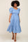 woman wearing a light blue smocked midi dress with puff sleeves and tiered skirt