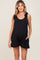 woman wearing a black sleeveless maternity romper with tied straps and pockets, showcasing a baby bump