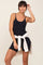 woman wearing a black spaghetti strap romper with a white sweatshirt tied around her waist