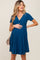 woman wearing a teal short sleeve maternity dress with a pleated skirt and holding her baby bump