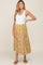 woman wearing a white tank top and a mustard yellow floral midi skirt with brown sandals