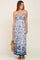 woman wearing a blue and white floral maxi dress with a straw bag and brown sandals