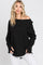 woman wearing a black long sleeve off the shoulder top and white pants